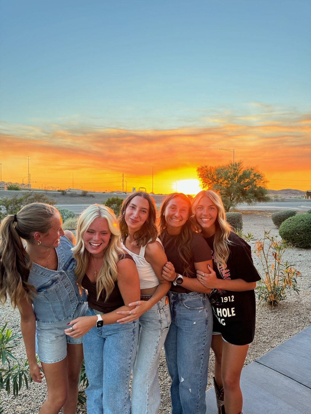 A group of friends laughing together at sunset on a desert trip